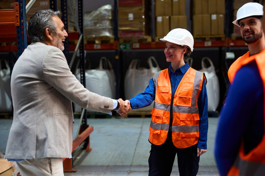 Warehouse manager shaking hands with female worker