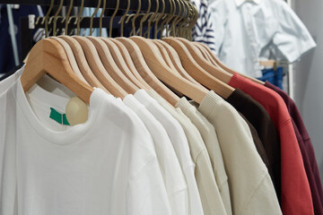 Knitted sweaters on hangers in shop for sale.