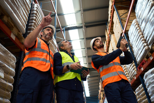 Warehouse workers collaborating on inventory management in storage facility - Powered by Adobe