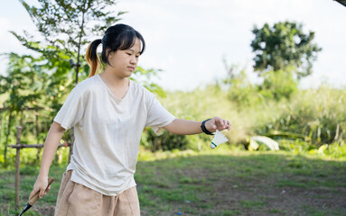 A girl preparing to serve a shuttlecock while playing badminton outdoors.