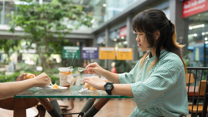 Teen girl eating dessert at an outdoor cafe table.