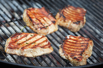 Pork chops grilling on a barbecue grate outdoors