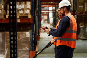 Warehouse workers managing inventory with scanner and pallet jack
