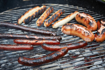 Sausages grilling on barbecue charcoal grill outdoors