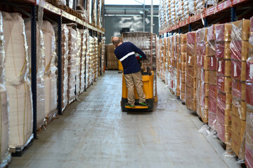 Worker operating electric pallet truck in warehouse aisle © alvaro