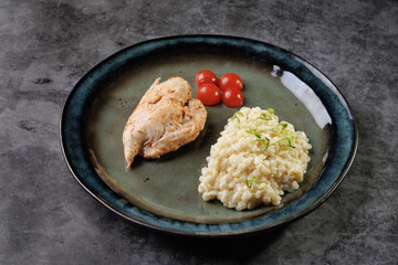 Gourmet Chicken With Creamy Risotto And Cherry Tomatoes On A Blue Plate