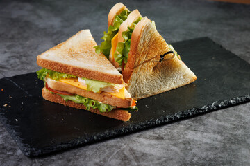 Toasted Sandwich With Lettuce, Tomato, Cheese and Ham, Triangular Slices on Slate Surface