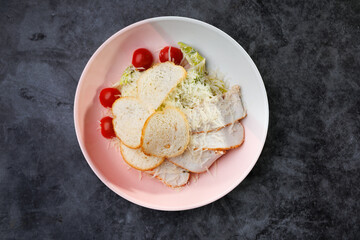 Fresh Caesar Salad With Grated Cheese, Cherry Tomatoes, and Slices of Bread on a Pink Plate