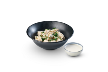 Pelmeni dumplings with sour cream and dill in a bowl
