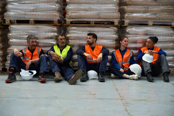 Diverse warehouse workers taking break, having conversation