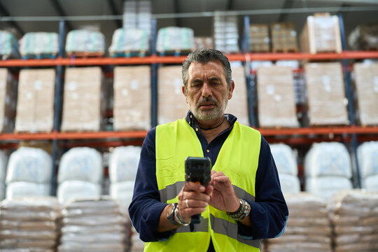 Mature warehouse worker scanning inventory in logistics distribution center
