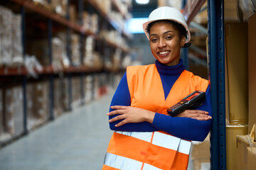 Female warehouse worker smiling, holding scanner, overseeing logistics