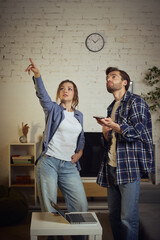 Couple pointing upward while discussing home issue in living room. Concept of household...