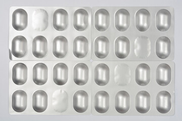 Four silver blister packs, each containing several light-colored, oval capsules for a 7-day dosage, are arranged in a grid on a white background
