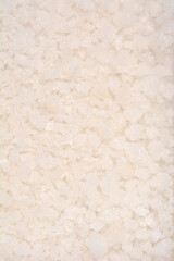 A vertical, close-up, high-angle texture shot fills the frame with coarse, irregular white and off-white crystals of natural sea salt