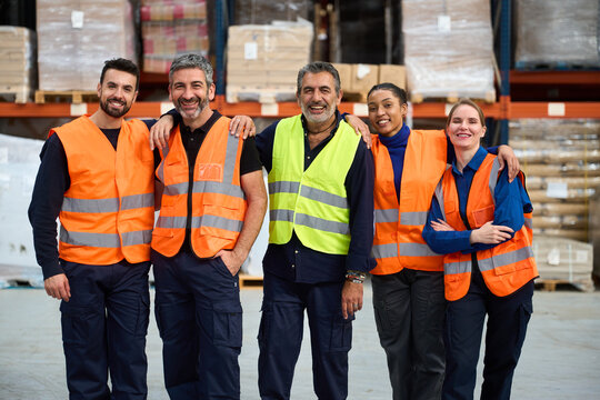Diverse group of warehouse workers smiling with arms around each other