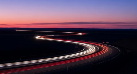 Long exposure light trails on a winding road at twilight.