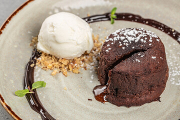Warm chocolate lava cake with melting center served with vanilla ice cream, cookie crumbs, and chocolate sauce for dessert menu and sweet food advertising