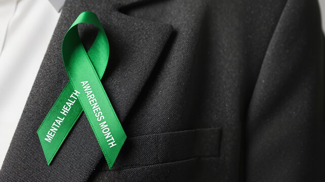 Close-up of green awareness ribbon on suit for Mental Health Awareness Month