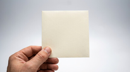 Obraz premium Male Hand Holding Blank Square Card Mockup Isolated on White Background