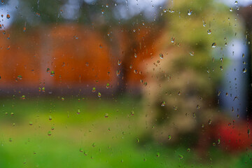 Raindrops on the window with a bokeh garden background during late Autumn or Fall