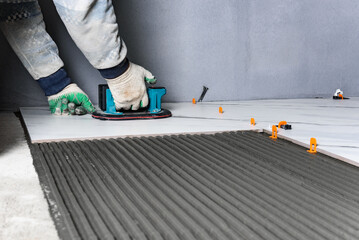 Laying the tiles using electric suction cup with automatic pumping.