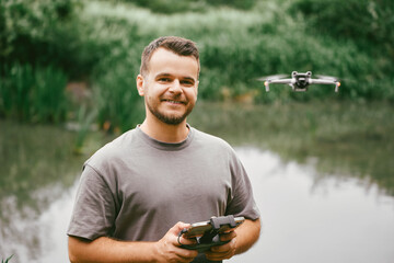 Man holding drone remote in green field.