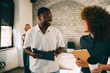 Smiling diverse colleagues, an African American man and a caucasian woman, have a relaxed and engaged discussion during a break in the office