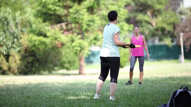 Two women playing frisbee in a sunny park - Powered by Adobe
