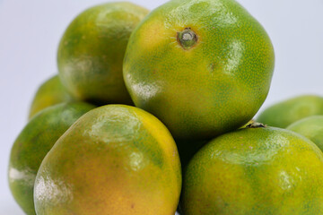 A Pile Of Citrus Fruits With Green Peels. Could Represent Unripe Fruit Or Specific Green Varieties.
