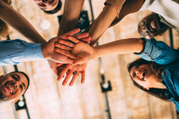 Low angle shot of a diverse business team stacking hands in the center, symbolizing unity, goals, and teamwork
