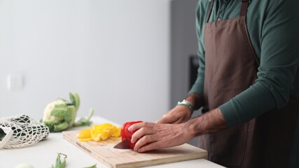 Man chef chopping bell pepper on cutting board