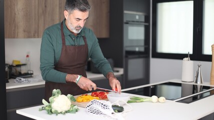 Mature man cooking fresh vegetables in modern kitchen