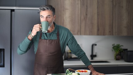 Middle aged man drinking coffee in modern kitchen
