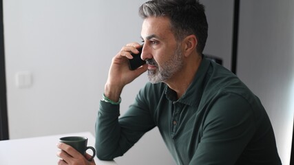 Man talking on phone holding coffee mug