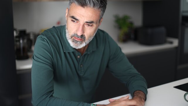 Mature man thinking seriously with concern in kitchen