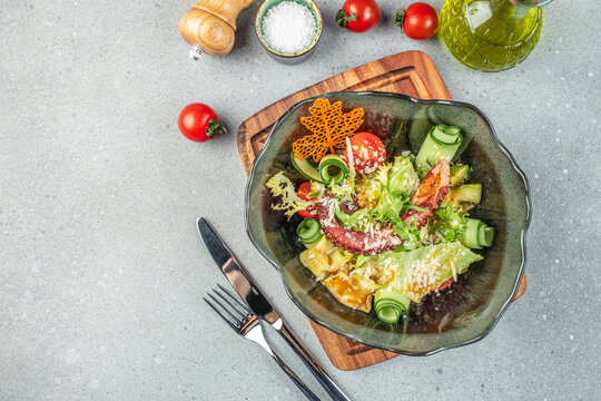 Gourmet octopus and vegetable salad with fresh greens, cucumber ribbons, tomatoes and parmesan served in an elegant bowl on a textured tabletop for menu design and food advertising - Powered by Adobe