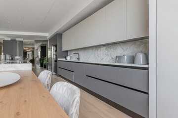 Minimalist L-shaped kitchen with an integrated flat extractor hood and floor-to-ceiling cabinets in graphite gray