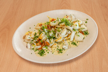 Grilled cuttlefish in its own ink, served with a garlic and fresh parsley sauce, accompanied by roasted potatoes and lemon