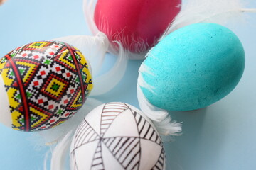 Vibrant Pysanka and Dyed Easter Eggs with Soft Feathers on Blue Background