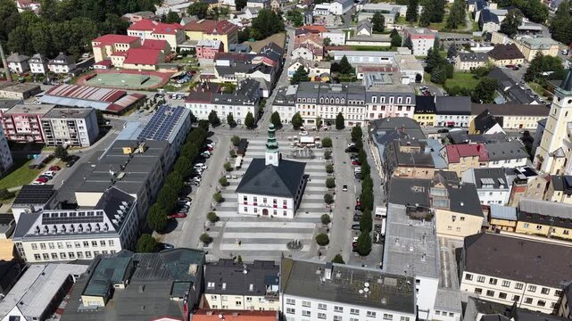 Aerial drone view of Jesenik town in Czech Republic showcasing the central market square and historic buildings nestled in Jeseniky Mountains, panoramic urban landscape in sunny summer day