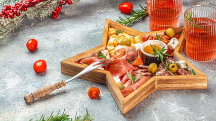 Festive charcuterie board in a wooden star tray with assorted meats, cheeses, olives and holiday decorations for Christmas menu and seasonal food advertising