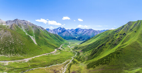 Aerial view of winding road and river with green mountain valley natural landscape in Xinjiang, China.
