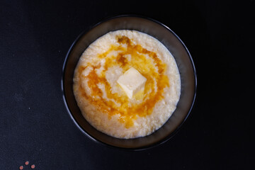 Creamy Oatmeal With Butter And Honey Swirl In A Black Bowl On A Dark Surface