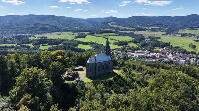 Aerial drone view of Zulova town in the Czech Republic historic church on Bozi Hora hill, traditional rooftops, surrounding greenery, and the peaceful town layout captured in clear daylight