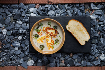 Creamy Soup With Cheese and Herbs in a Blue Bowl, Served With Toasted Bread Slice