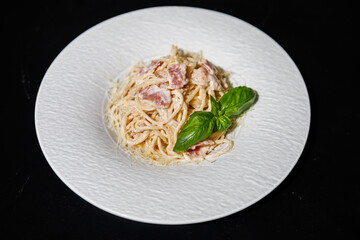 Creamy Bacon Spaghetti Carbonara With Basil Garnish On White Plate