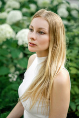 A blonde woman with green eyes in a garden
