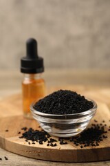 Black cumin seeds and oil on wooden table, closeup