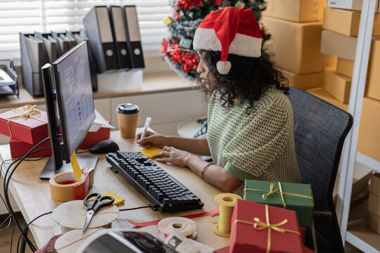 Small business holiday warehouse process showing a worker hold Christmas gifts, checking orders, arranging parcels, managing stock accuracy and coordinating ecommerce busy shipping for festive season